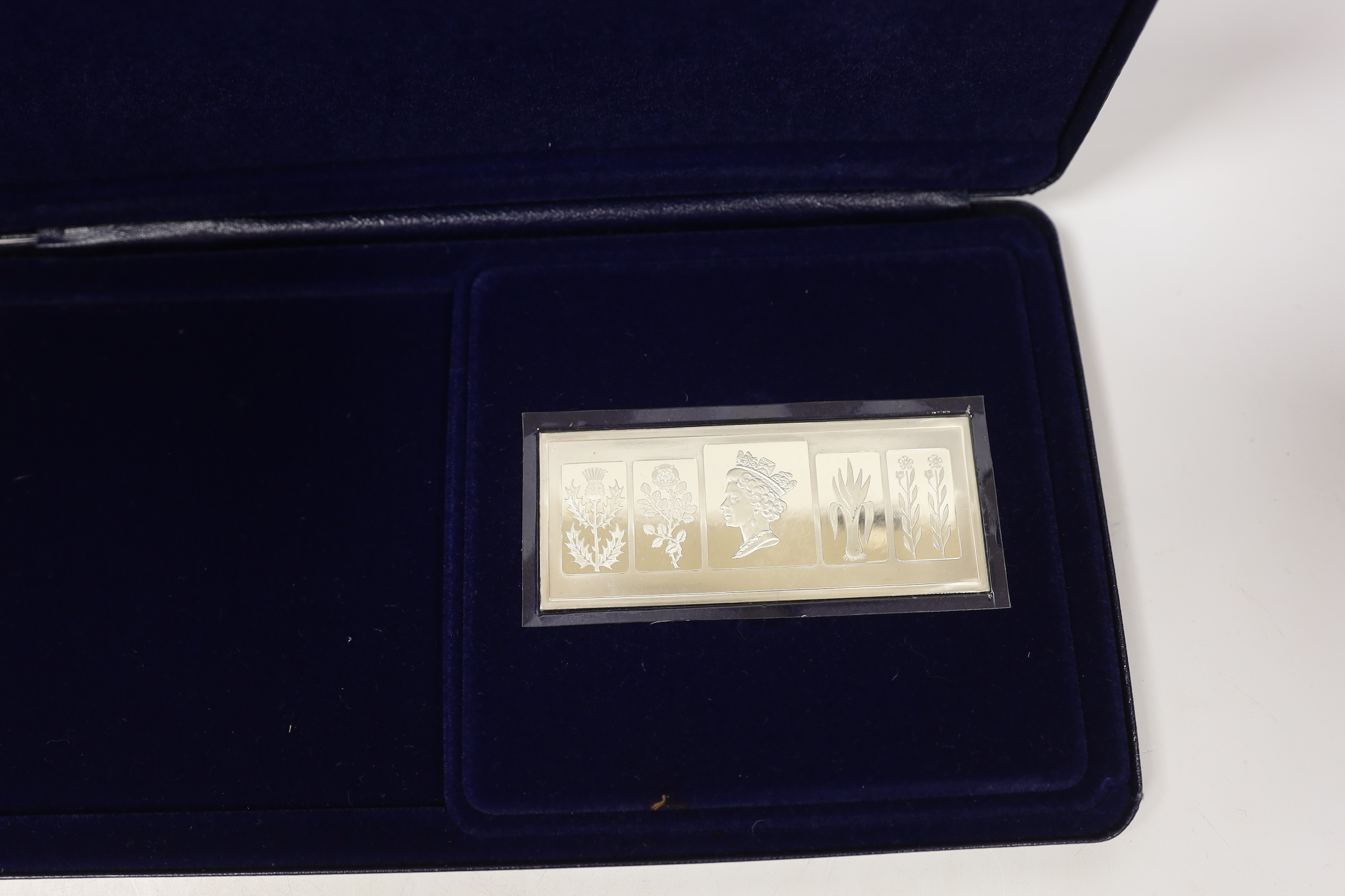 A cased Danbury Mint Queen Elizabeth II Silver Jubilee silver ingot and a Pobjoy Mint 25th anniversary of the Queen's coronation twin silver gilt medallions and First Day covers album